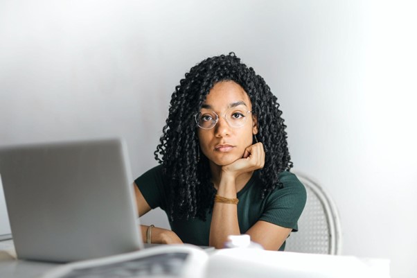 a woman looks sad at a computer because of digital distractions and clutter.