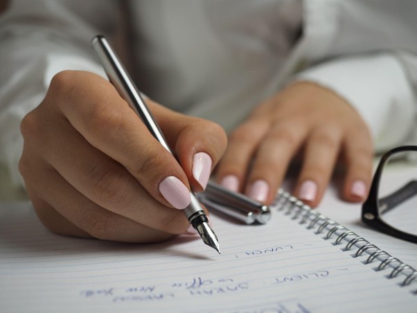 A woman making a list of tasks to delegate before hiring a virtual assistant.
