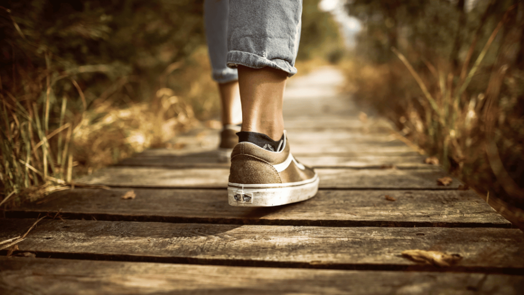 A person in sneakers strolls along a wooden path, enjoying a moment of tranquility away from digital notifications.